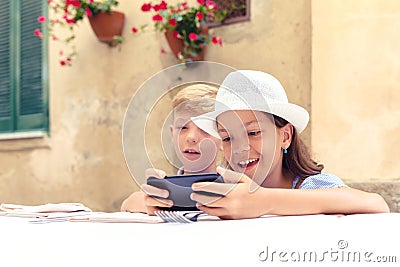 Happy kids playing with momâ€™s smartphone waiting for food at restaurant Stock Photo